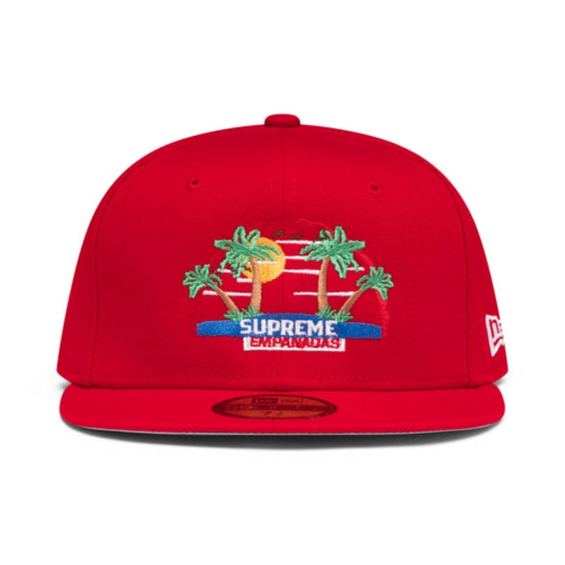 Red baseball cap with an embroidered design of palm trees, a sun, and "Supreme Empanadas" text.
