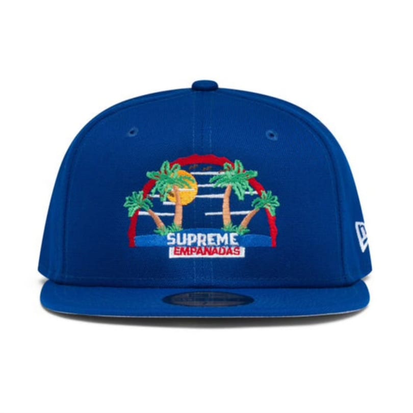 Blue Supreme Empanadas baseball cap with an embroidered tropical sunset and palm trees logo.